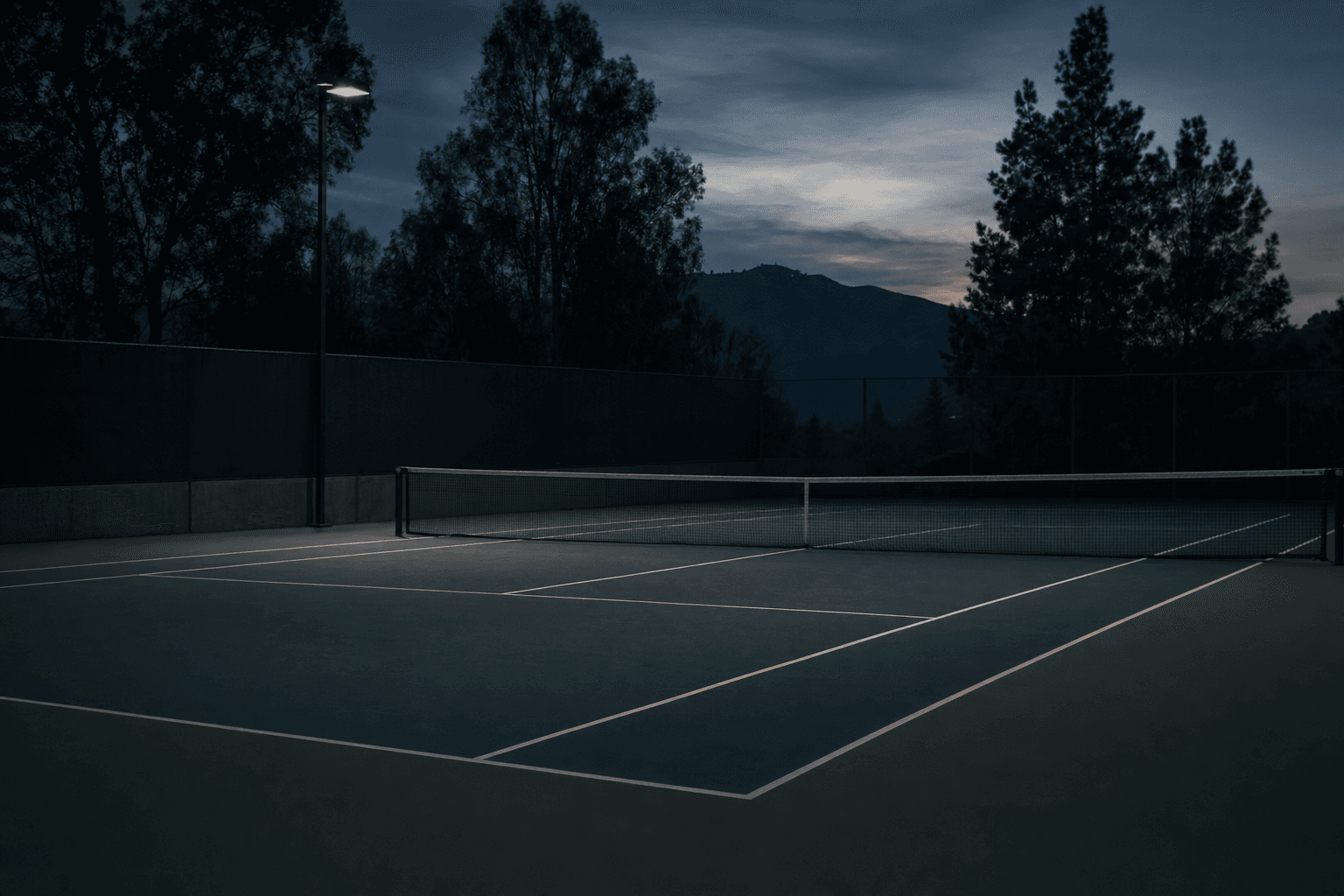 Empty tennis court at dusk in dusty-blue twilight